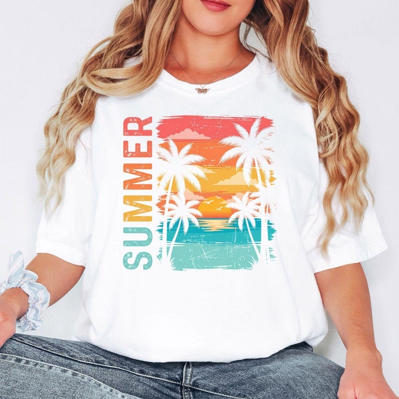 May include: White t-shirt with a vibrant summer design. The graphic depicts palm trees, a sunset, and the word "SUMMER" in vertical text. The shirt has a casual, relaxed fit.