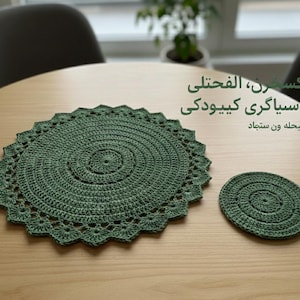 May include: An olive green crochet placemat and coaster set. The round placemat has a scalloped edge and a spiral pattern. The coaster is also round with a spiral design. The image includes text in a foreign language.