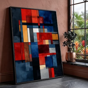 Pode incluir: Impressão de arte abstrata emoldurada. A obra apresenta um design geométrico com blocos vermelhos, azuis, laranja, brancos e pretos. A pintura está encostada a uma parede ao lado de uma janela com uma pequena planta em vaso.