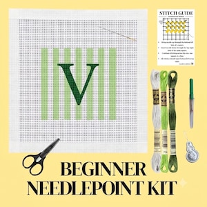 May include: A needlepoint kit featuring a white canvas with a green letter V and vertical stripes, a needle, black scissors, three skeins of embroidery floss in white, light green, and dark green, a needle threader, and a printed stitch guide.