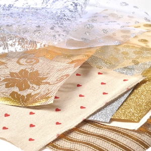 Puede incluir: Una variedad de telas decorativas con diversas texturas y patrones. Incluye flores doradas, purpurina plateada y tela crema con corazones rojos. Ideal para manualidades y decoración.