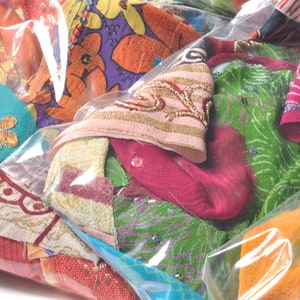 May include: A clear plastic bag filled with colorful fabric scraps. The scraps are made of various materials, including silk, cotton, and velvet. They are decorated with embroidery, sequins, and beads. The scraps are in a variety of colors, including red, green, blue, pink, and orange.