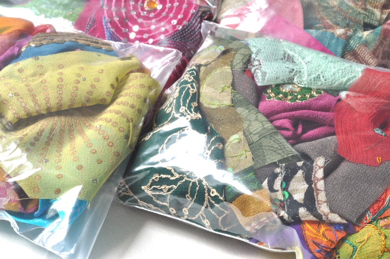 May include: Assortment of colorful fabric scraps in clear plastic bags. The fabrics are a mix of textures, including lace, sequins, and embroidery.