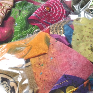 May include: A plastic bag filled with colorful fabric scraps. The scraps are a variety of textures and patterns, including floral, geometric, and paisley. Some of the scraps have sequins or embroidery.