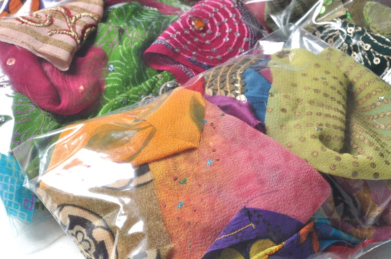 May include: A plastic bag filled with colorful fabric scraps. The scraps are a variety of textures and patterns, including floral, geometric, and paisley. Some of the scraps have sequins or embroidery.
