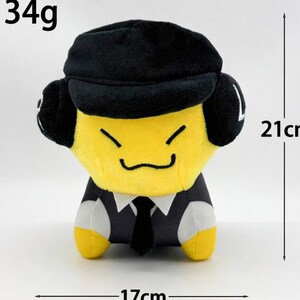 May include: A plush toy with a yellow face, black hat, and a black suit with a tie. The toy is 21cm tall and 17cm wide, weighing 134g. The toy has a smiling face.