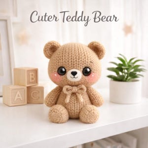 May include: A handmade, tan-colored knitted teddy bear with a bow tie, rosy cheeks, and large black eyes. The text "Cuter Teddy Bear" is above the bear. The bear is sitting on a white surface, with wooden blocks and a small plant in the background.