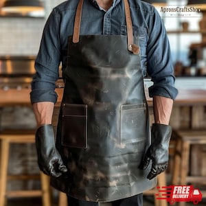 May include: A black leather apron with brown leather straps and two front pockets. The apron is worn with black gloves. The text "ApronsCraftShop" is visible in the upper right corner. The words "FREE DELIVERY" are visible in the lower right corner.