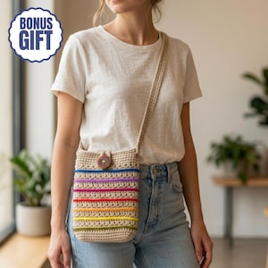 Op de afbeelding: Een beige gehaakte crossbodytas met een regenboogstreepontwerp. De tas heeft een lange riem en een kleine, ronde knoopsluiting. De tekst "BONUS GIFT" staat in een blauw-witte cirkel linksboven.