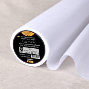 Könnte beinhalten: Eine Rolle weißen Vliesstoffs. Das Etikett trägt die Aufschrift "THERMOCOLLANT" und enthält französischen Text. Die Rolle ist 90 cm breit und 25 Meter lang. Der Stoff besteht aus 50 % Polyester und 50 % Polyamid.