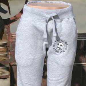 May include: Gray sweatpants with a skull graphic and the text "A Little Bit Dramatic".