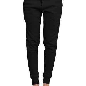 May include: Black sweatpants with a drawstring waist and elastic cuffs. The pants have two front pockets and are paired with white slip-on shoes. The casual pants are made of a soft material.