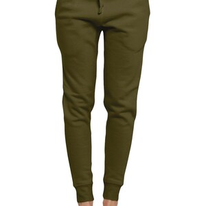 May include: Olive green sweatpants with a drawstring waist and elastic cuffs. The pants have two front pockets and are made of a soft, comfortable material. The model is wearing white slip-on shoes.