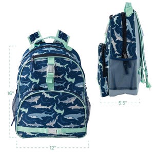 May include: A navy blue backpack with a shark pattern, measuring 16 inches high, 12 inches wide, and 5.5 inches deep. It features a front pocket, side mesh pockets, and mint green accents on the straps and buckles. The backpack is designed with a repeating pattern of various shark species.
