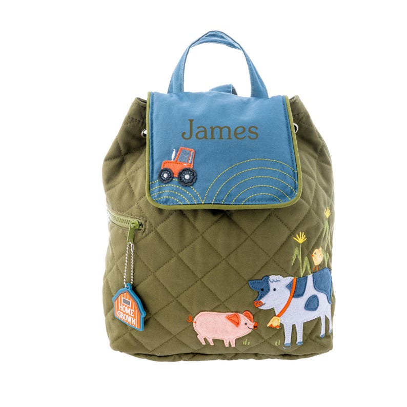 May include: A green quilted backpack with a blue flap featuring the name "James" embroidered on it. The flap also has a small orange tractor embroidered on it. The backpack has a small charm attached to it that says "Home Grown". The backpack also has a cow, pig, and chick embroidered on it.