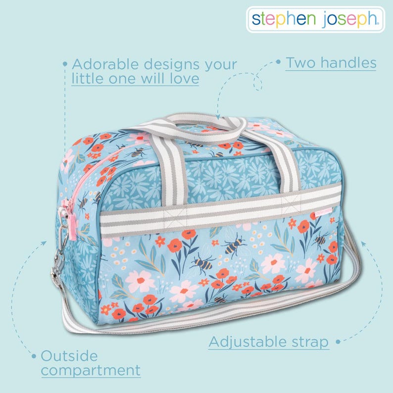 May include: A light blue duffel bag featuring a floral and bee pattern with red and white flowers. The bag includes two striped handles, an adjustable shoulder strap, and an outside compartment. The Stephen Joseph logo is visible at the top.