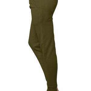 May include: Olive green joggers with a relaxed fit, featuring a front pocket and elastic cuffs. The pants are paired with white slip-on shoes, creating a casual and comfortable look. The fabric appears to be a soft, knit material.