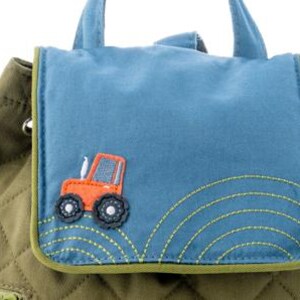 May include: A green quilted backpack with a blue flap featuring an orange tractor applique. The flap has green stitching around the edges and a small pocket with a zipper.