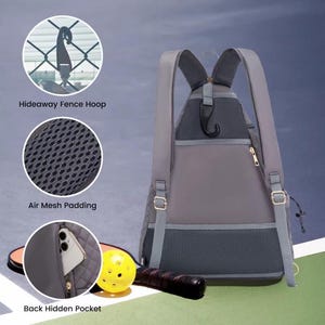 K&ouml;nnte beinhalten: Grauer Rucksack mit einer versteckten Tasche, atmungsaktivem Mesh-Polster und einem versteckten Zaunhaken. Der Rucksack ist auf einer gr&uuml;nen Oberfl&auml;che mit einem gelben Ball und einem Holzschl&auml;ger abgebildet.