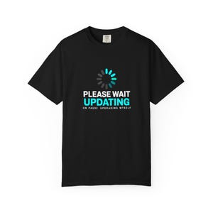 Pode incluir: Uma t-shirt preta de manga curta com um gráfico de um ícone de carregamento circular em cinzento e ciano. Abaixo do ícone, o texto diz PLEASE WAIT UPDATING em branco e ciano, seguido pelo texto mais pequeno em branco ON PAUSE UPGRADING MYSELF.