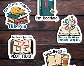 May include: A collection of five colorful stickers with book-themed designs. One sticker features a cat sleeping on books, labeled "Emotional Support TBR Pile." Other stickers say "I'm Reading," "Plot Twist," "Escape Reality," and "Over Caffeinated."