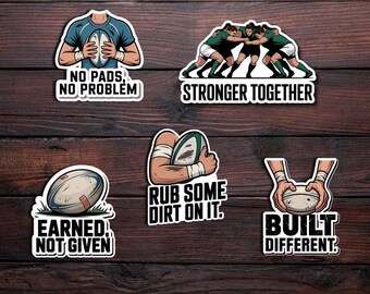 May include: Set of five rugby-themed stickers with various designs and text. The stickers feature illustrations of rugby balls, players, and phrases like "No Pads, No Problem" and "Stronger Together." The stickers are on a dark wood background.