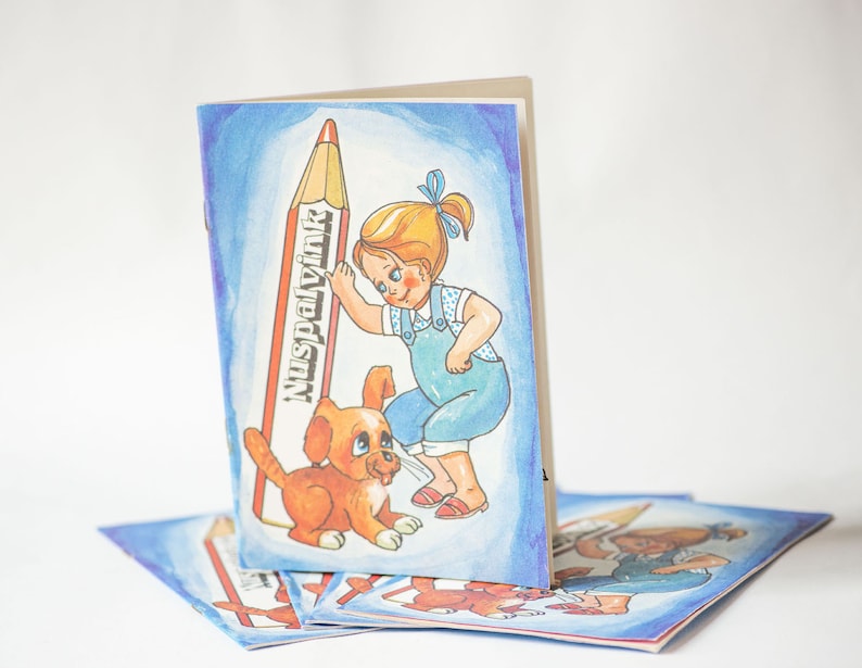 May include: A colorful illustration of a girl and a puppy standing next to a large red crayon. The crayon has the word "Nuspalvin" written on it. The girl is wearing a blue overall dress and has blonde hair. The puppy is brown and white. The illustration is on a blue background.