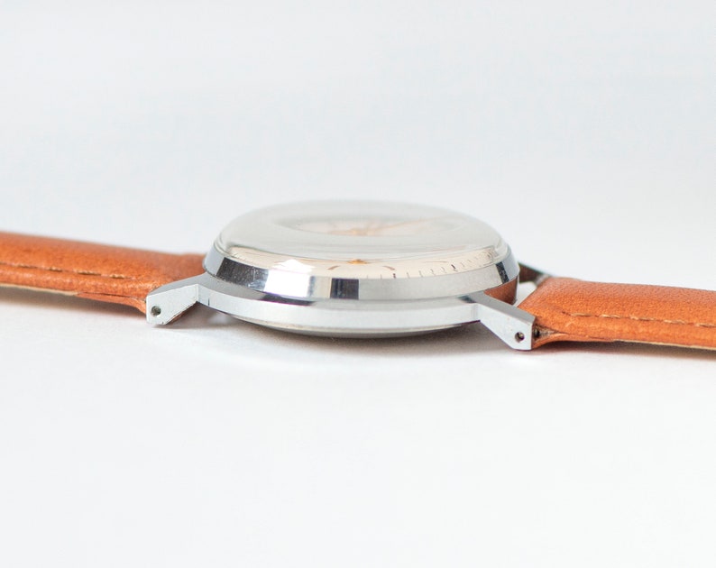 May include: A silver wristwatch with a white face and a brown leather band.