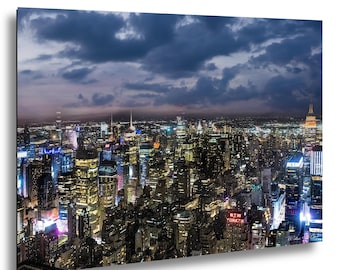 May include: A nighttime view of New York City, showcasing illuminated skyscrapers under a dark blue, cloudy sky. The image highlights the city's lights and the 'New Yorker' sign.