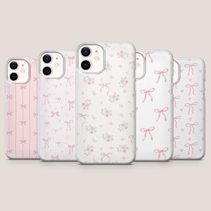 May include: Five clear smartphone cases arranged in a row, each featuring a unique pink pattern. Designs include vertical stripes with bows, scattered bows with sparkles, small pink floral clusters, repeating pink bows, and bows with hearts.