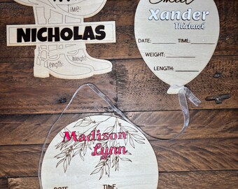 May include: Wooden baby announcement signs in the shape of a cowboy hat, boot, and balloon. The signs include the names "Nicholas", "Xander Michael", and "Madison Lynn", with spaces for date, time, weight, and length.