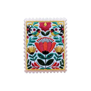 Può includere: Toppa ricamata con un design floreale e di uccelli. La toppa presenta un fiore rosso centrale, fiori gialli e rossi e due uccelli. Lo sfondo è azzurro con foglie e steli verdi. La toppa ha la forma di un francobollo con bordo smerlato.