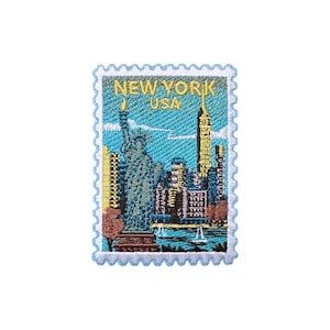 Puede incluir: Parche bordado con forma de sello postal con el horizonte de la ciudad de Nueva York. El diseño incluye la Estatua de la Libertad, rascacielos y el texto "NEW YORK USA" en amarillo.