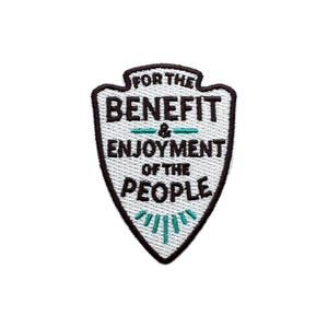 May include: Embroidered patch in a shield shape with the text "FOR THE BENEFIT & ENJOYMENT OF THE PEOPLE". The patch is white with black and teal accents. The text is in a bold, sans-serif font.