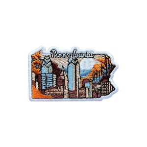 Peut inclure: Écusson brodé en forme de la Pennsylvanie, représentant un paysage urbain aux teintes bleues, marron et orange. Le mot "Pennsylvania" est brodé en cursive en haut. L'écusson a une bordure blanche.