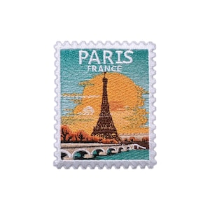 May include: Embroidered patch depicting the Eiffel Tower in Paris, France, with a sunset backdrop. The design mimics a postage stamp, with the text "PARIS FRANCE" at the top. It has a white, scalloped border, and the image is in shades of brown, orange, and teal.