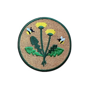 Könnte beinhalten: Runder, gestickter Aufnäher mit einem Löwenzahn- und Bienenmotiv. Der Aufnäher hat einen braunen Hintergrund und einen grünen Rand. Die Löwenzahnblüten sind gelb und die Bienen sind schwarz und gelb. Geeignet für Kleidung.