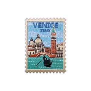 Può includere: Toppa ricamata a forma di francobollo con una scena di Venezia, Italia. La toppa mostra una gondola, edifici, un ponte e un'alta torre. Il testo "VENICE ITALY" è in alto, con un cielo azzurro chiaro e acqua turchese.