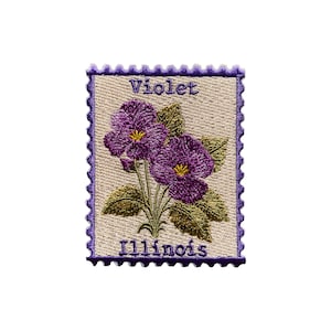 May include: Embroidered patch featuring a purple violet flower with yellow centers and green leaves. The patch is in the shape of a postage stamp with the words "Violet" and "Illinois" in purple text. The border is a scalloped purple.