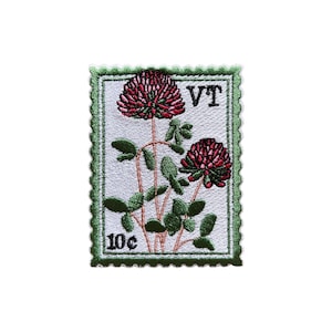May include: Embroidered patch in the shape of a postage stamp featuring two red clover flowers with green leaves and stems. The patch has a green border and the text "VT" and "10¢".