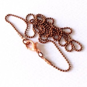 May include: A copper ball chain necklace with a lobster clasp closure.