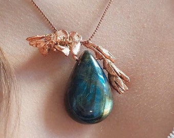 Op de afbeelding: Een koperen ketting met een blauwe labradorit-traan hanger en een koperen bloemenontwerp.