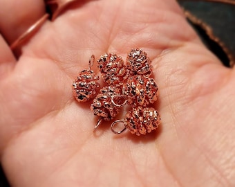 May include: A collection of six small, metallic rose gold charms shaped like pinecones. Each charm features a textured, bumpy surface and includes a small circular loop at the top for attachment, designed for use in jewelry making or crafting projects.