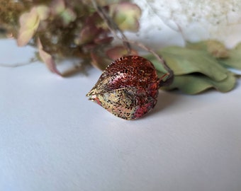 Op de afbeelding: Een delicate, ingewikkeld gepatroneerde, gouden en rode papieren lantaarn, die doet denken aan een Chinese lantaarn.