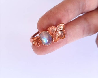 Anello con vero fiore di ortensia e cabochon in pietra di luna arcobaleno