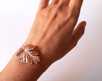 Op de afbeelding: Een armband van roségoud met een delicaat bladontwerp. De armband is verstelbaar en past om de meeste polsen.