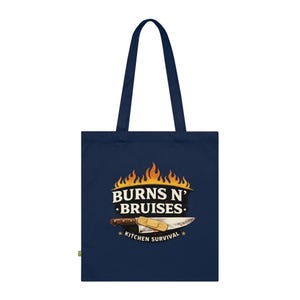 May include: A navy blue tote bag with a graphic that reads "BURNS N' BRUISES" above a knife and bandage illustration. The text "KITCHEN SURVIVAL" is below the image. The bag has two navy blue handles.