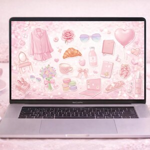 May include: A laptop displays a pink-themed digital collage of stickers, including a pajama set, rose, croissant, and perfume bottles. A cup of coffee, flowers, and a pair of wireless earbuds are in the foreground. The overall aesthetic is soft and feminine.
