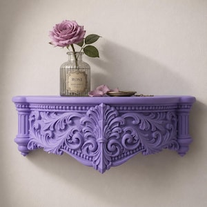 Könnte beinhalten: Ein lilafarbenes Wandregal mit aufwendigen, geschnitzten Details. Eine Glasflasche mit einer Rose und dem Text "ROSE PARFUMERIE PARIS" steht auf dem Regal, zusammen mit einer kleinen Schale. Das Regal ist an einer weißen Wand befestigt.