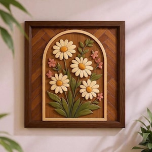 Könnte beinhalten: Ein Wandkunstwerk aus Holz mit einem geschnitzten Blumendesign. Das Kunstwerk zeigt Gänseblümchen mit weißen Blütenblättern und gelben Zentren, umgeben von grünen Blättern und kleinen rosa Blüten, eingebettet in einen bogenförmigen Rahmen. Der Rahmen ist dunkelbraun.